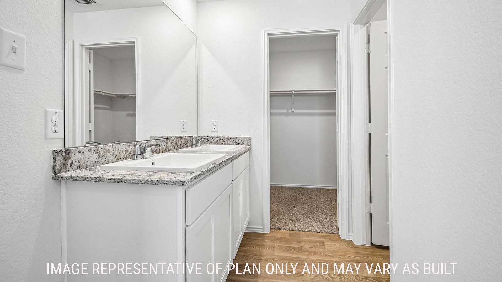 Iris primary bathroom with double vanity sink and view of primary bedroom walk-in closet.