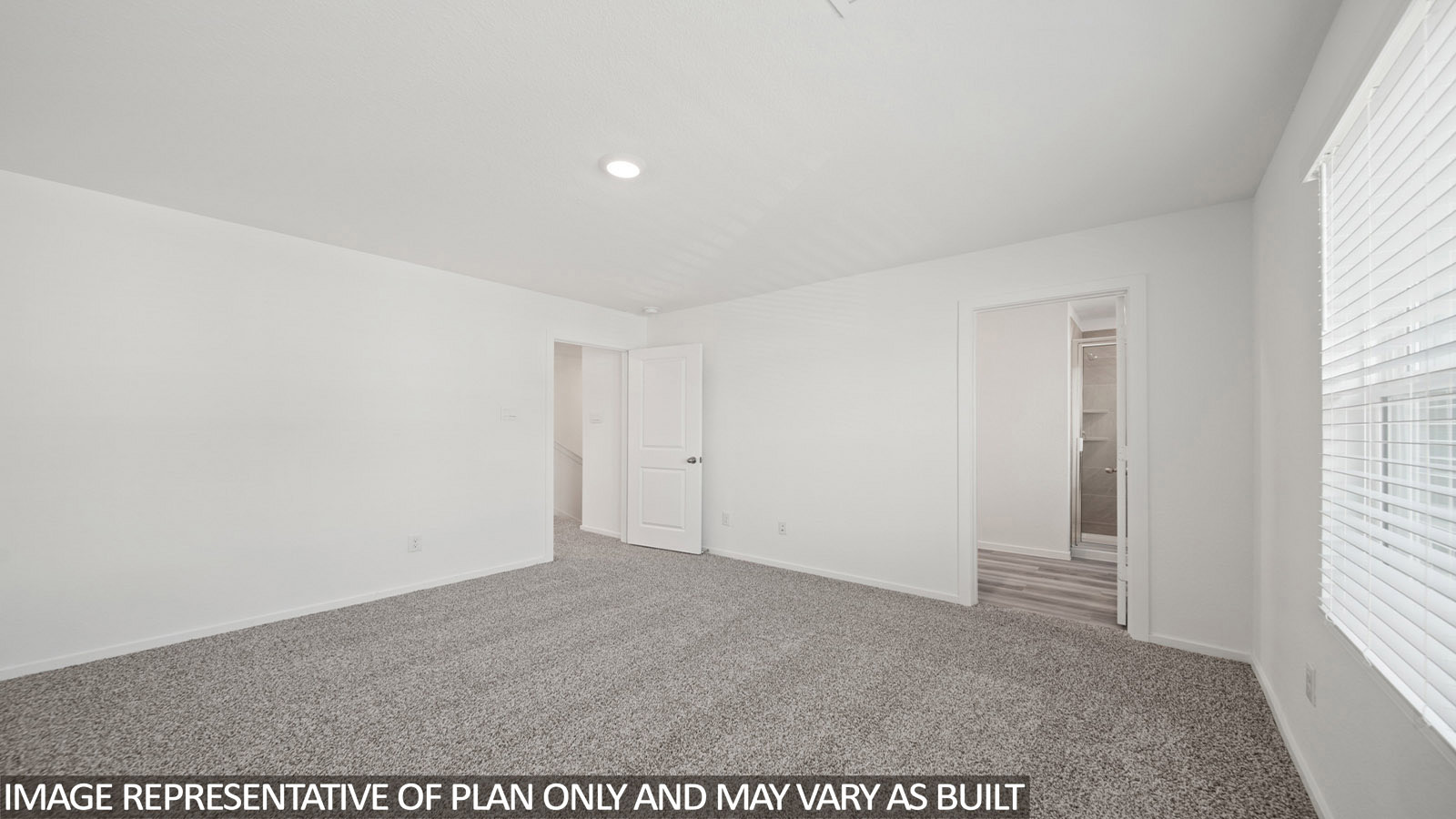 Iris primary bedroom with carpeted flooring and view of primary bathroom.