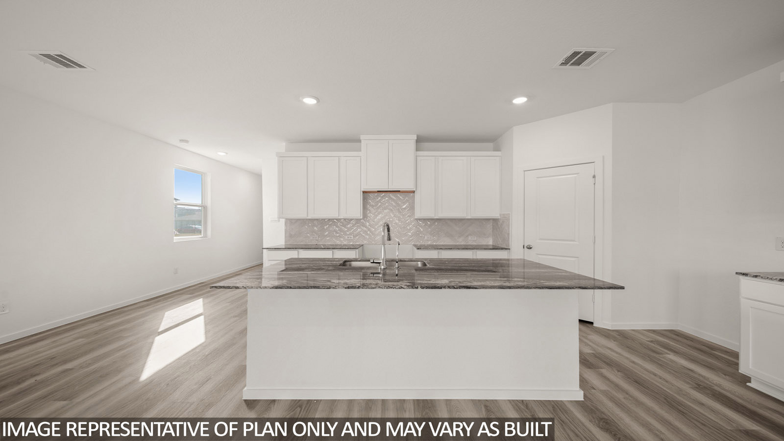 Jasmine kitchen with kitchen island with light cabinets and dark countertops and view of entry.