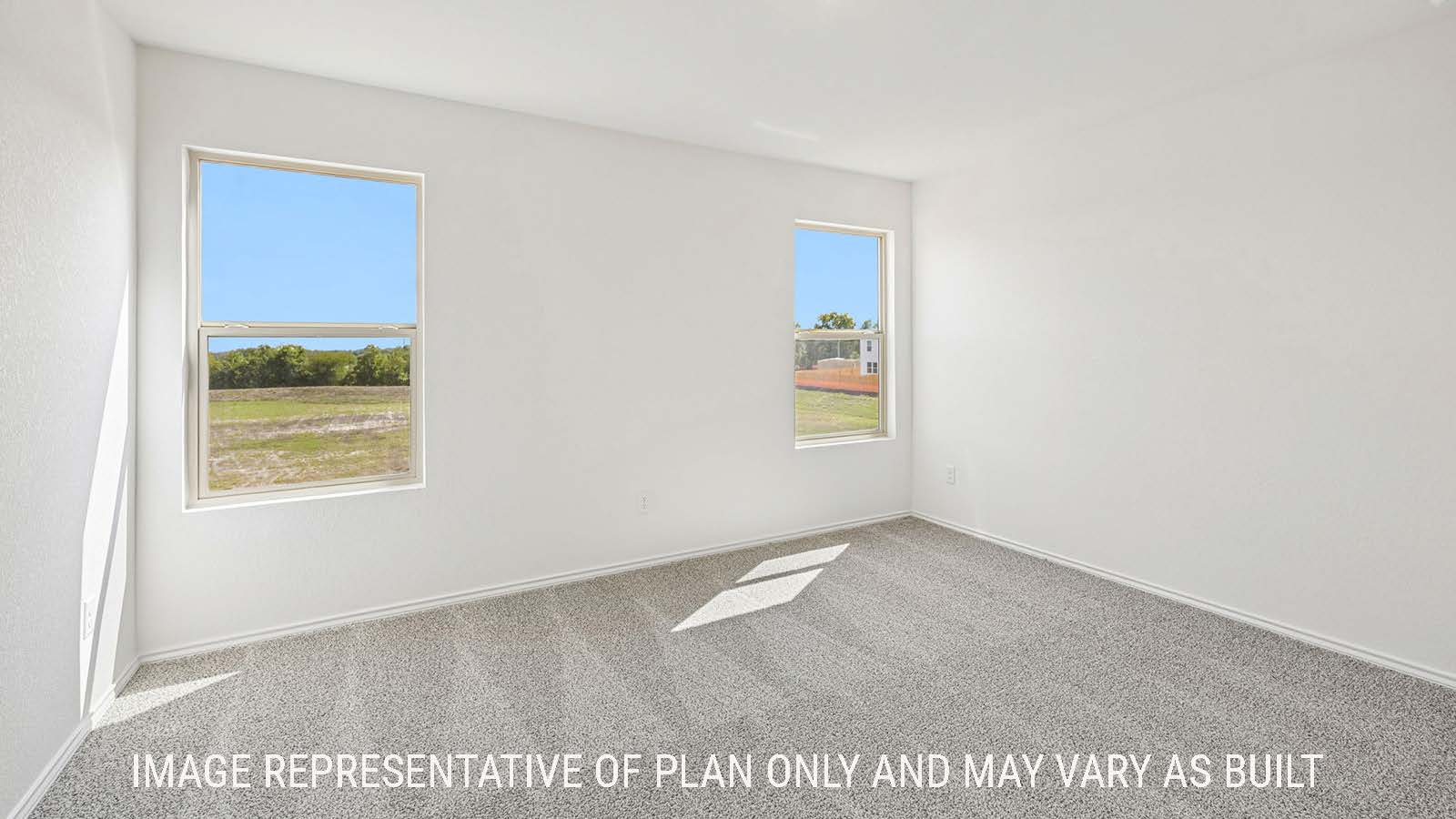 Jasmine primary bedroom with carpeted flooring and windows for natural lighting.