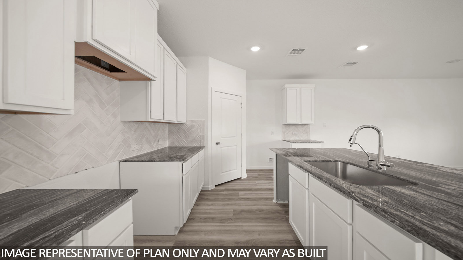 Jasmine kitchen with light cabinets and dark countertops with view of open concept dining room.