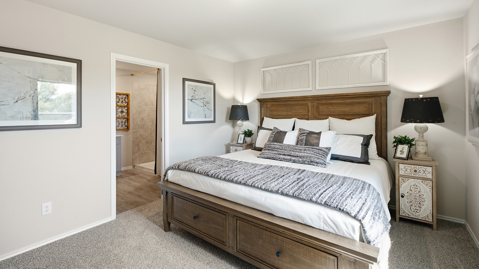 Hidden Trails Model Home primary bedroom with carpeted flooring and view of primary bathroom.