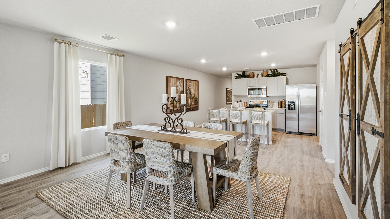 Hidden Trails Model Home dining room with view of open concept kitchen with windows for natural lighting.