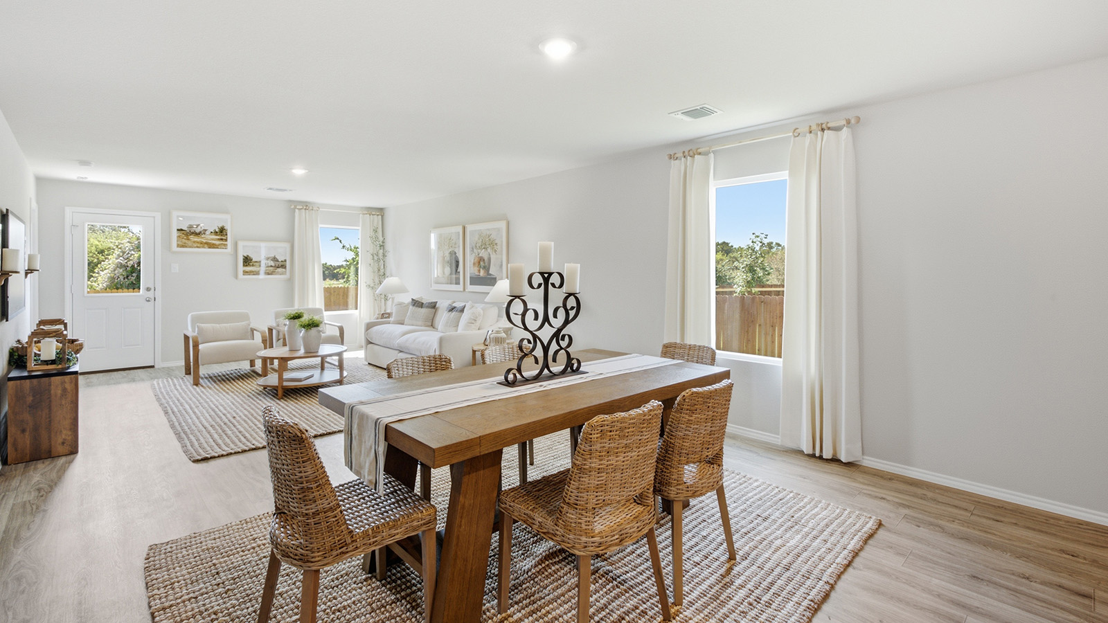 Hidden Trails Model Home dining room with view of open concept living room and windows for natural lighitng.