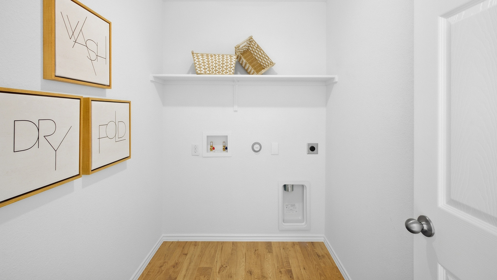 Wildwood Model utility room with washer and dryer connections and shelving for storage.