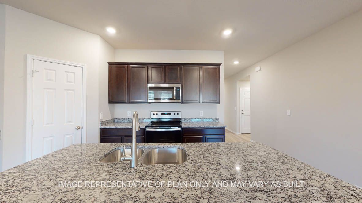 Texas Cali kitchen with large island and granite countertop with dark cabinets.