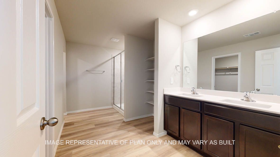 Seabrook primary bathroom with vinyl plank flooring, dark cabinets and white countertops.