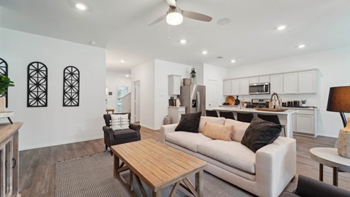 Open living room with windows, white walls, and vinyl wood flooring.