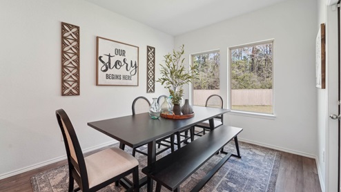 Dining room with backyard access, windows, white walls, and vinyl wood flooring.
