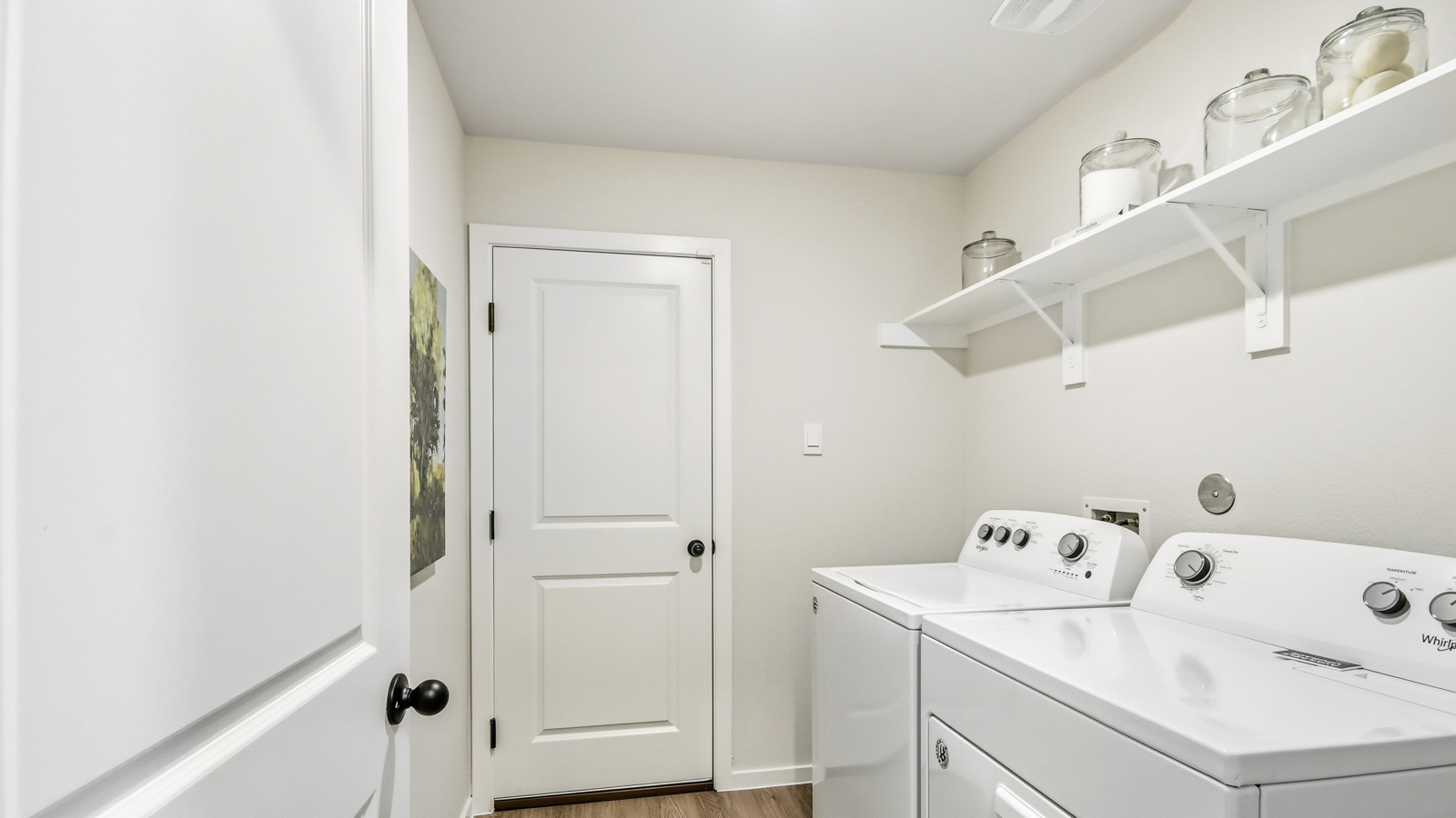 Utility room with storage located off the entry hallway and garage door