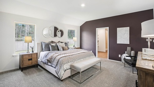 Primary bedroom with windows, white walls, and light carpet.