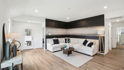 Open living room with windows, white walls, and vinyl wood flooring.