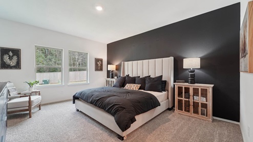 Primary bedroom with windows, white walls, and light carpet.