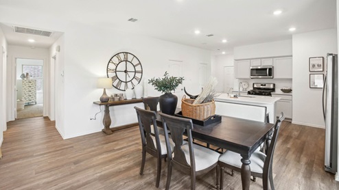 Open living room with windows, white walls, and vinyl wood flooring.