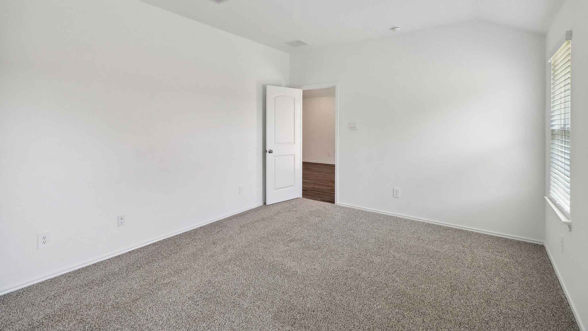 Primary bedroom with carpet flooring and a bright window.