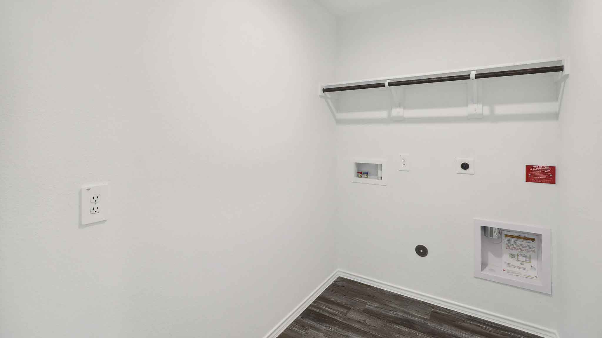 Utility room with vinyl flooring and overhead storage space.
