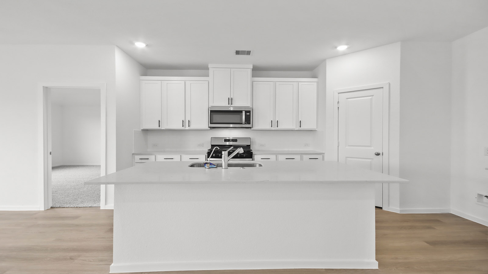 Kitchen with quartz countertops and marden hardware and an island and vinyl floor