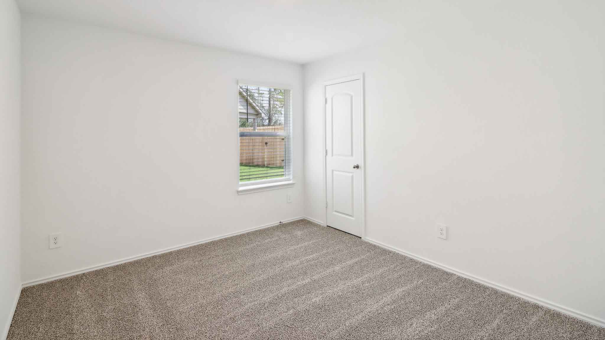 Secondary bedroom with carpet flooring and a bright window.