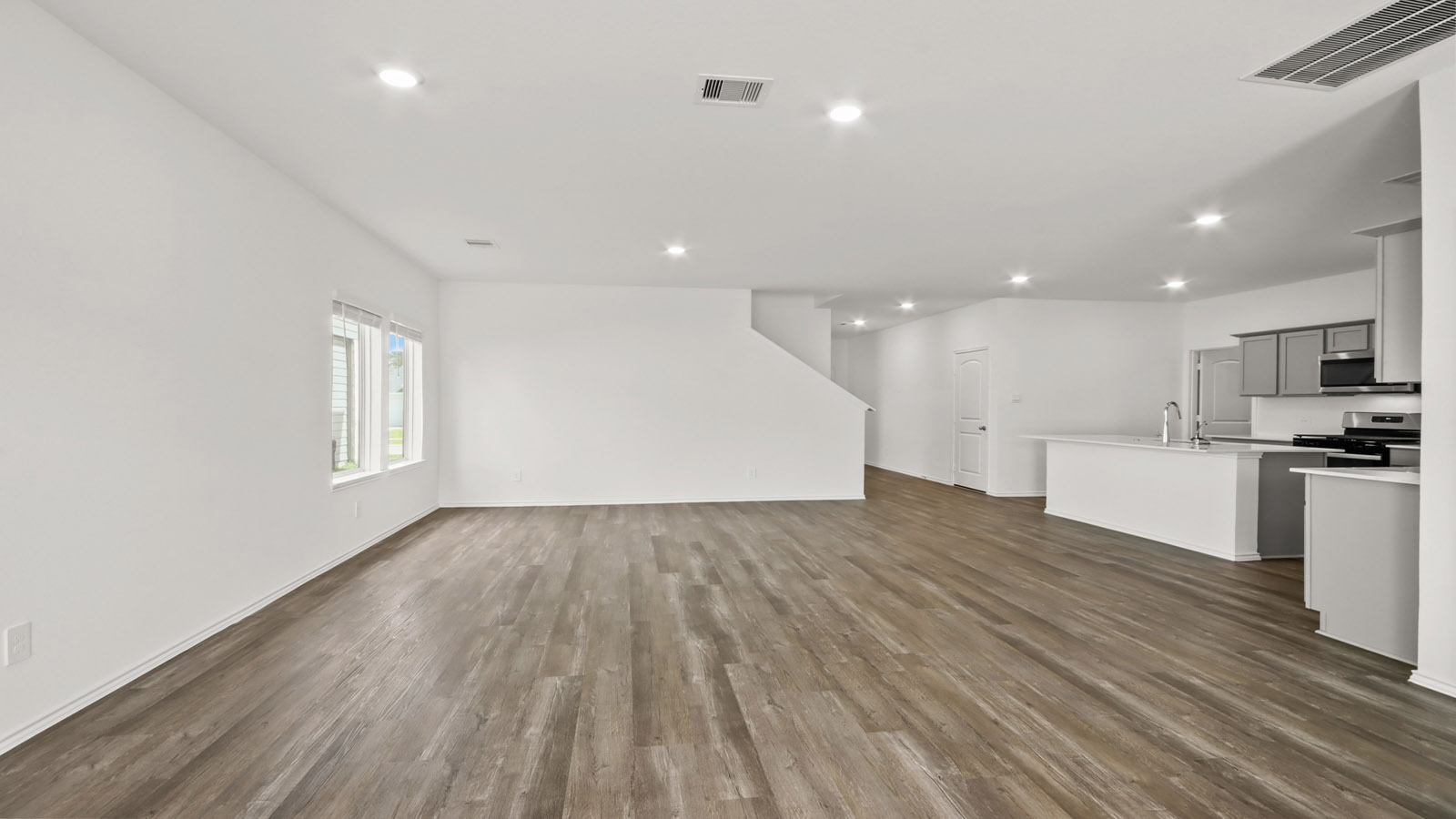 Open concept living, dining, and kitchen area with vinyl flooring and bright windows