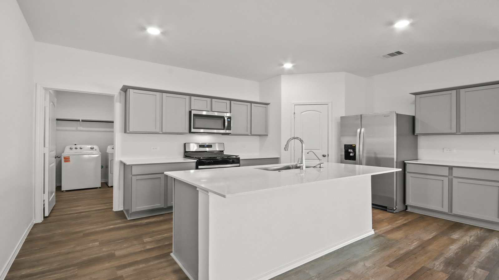 Kitchen with quartz countertops and marden hardware and an island and vinyl floor