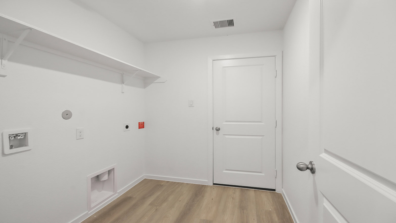 Utility room with storage located off the entry hallway and garage door