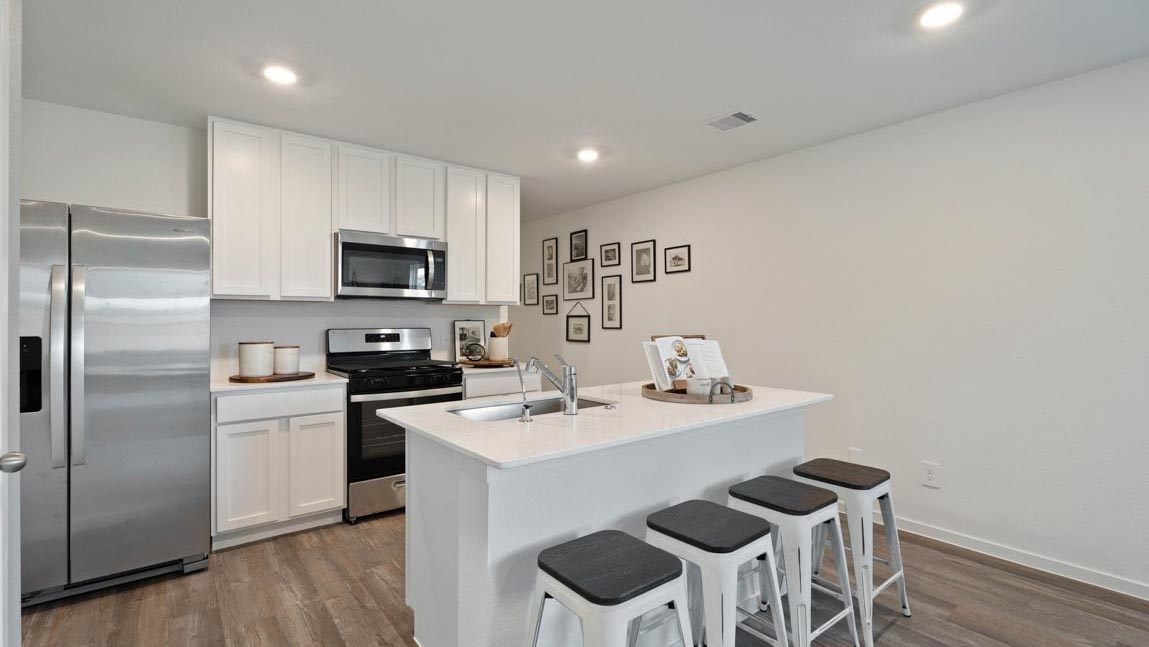 Kitchen with quartz countertops and marden hardware and an island and vinyl floor