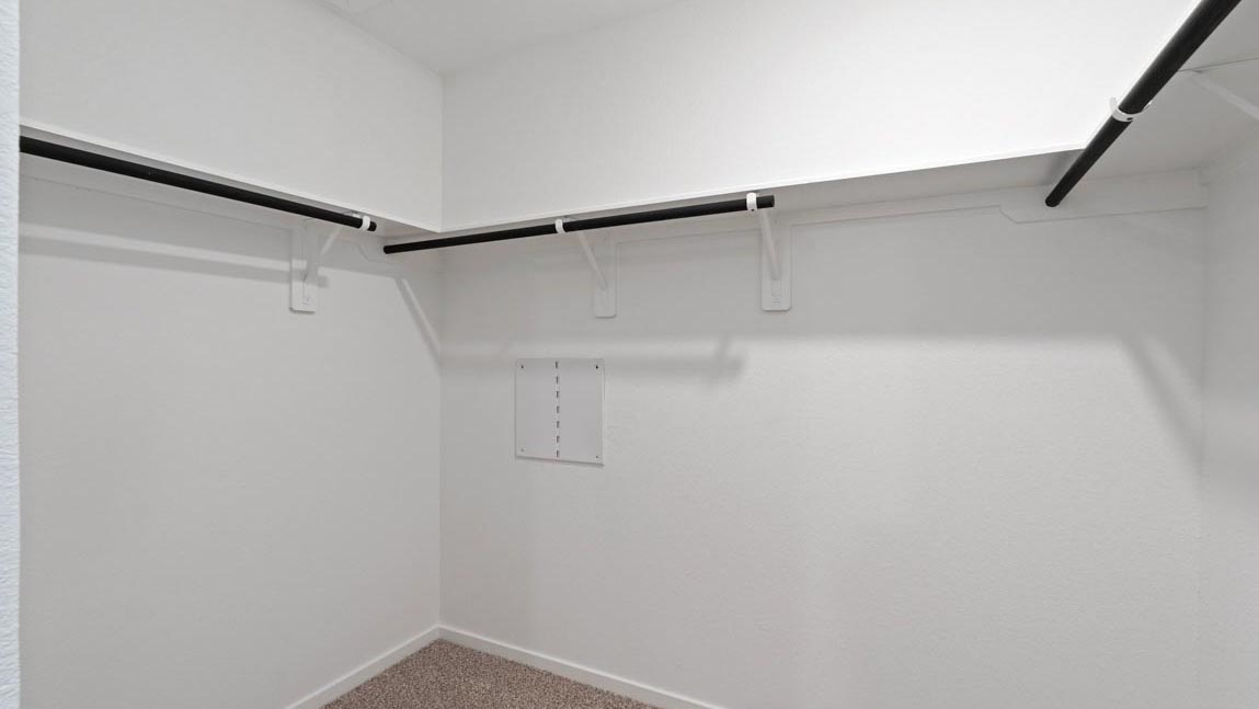 Primary bedroom walk-in closet with carpet flooring in Mill Creek community in Magnolia TX