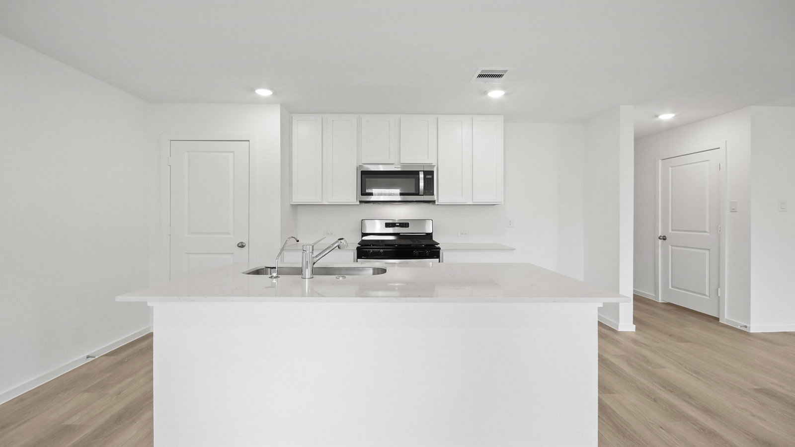 Kitchen with quartz countertops and marden hardware and an island and vinyl floor
