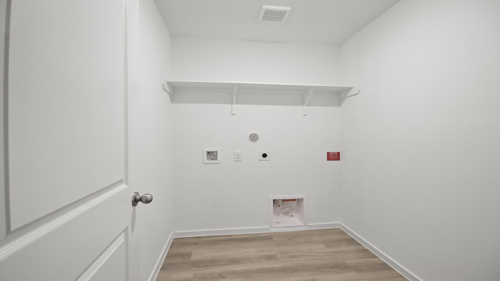 Utility room with storage located off the entry hallway and garage door