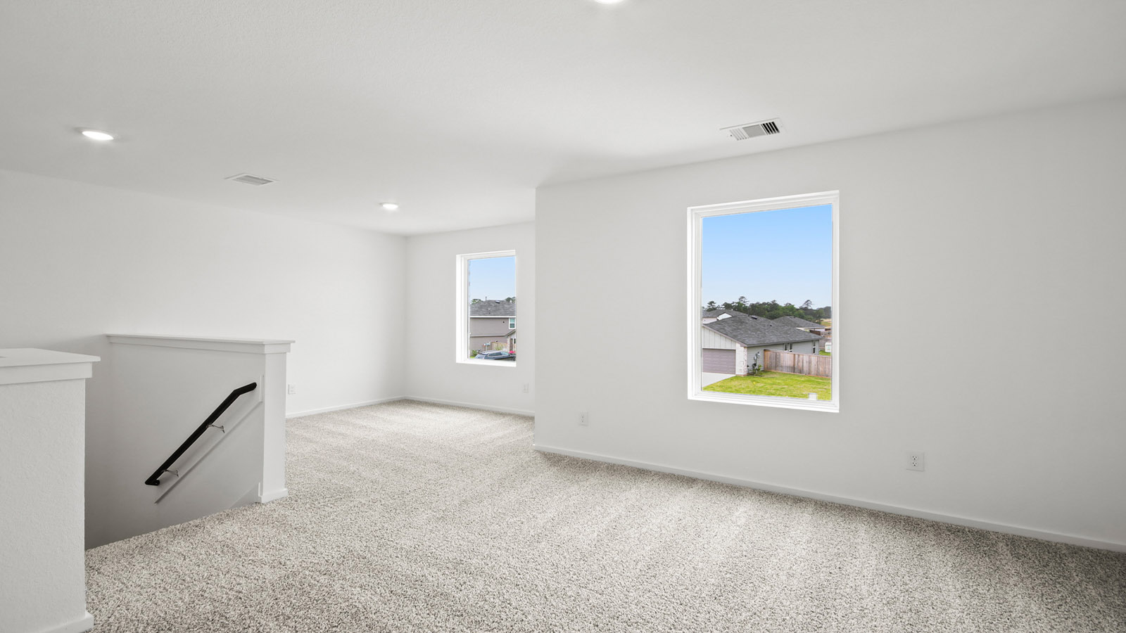 Second story game room with carpet flooring with bright windows in this multi functional space in Magnolia TX