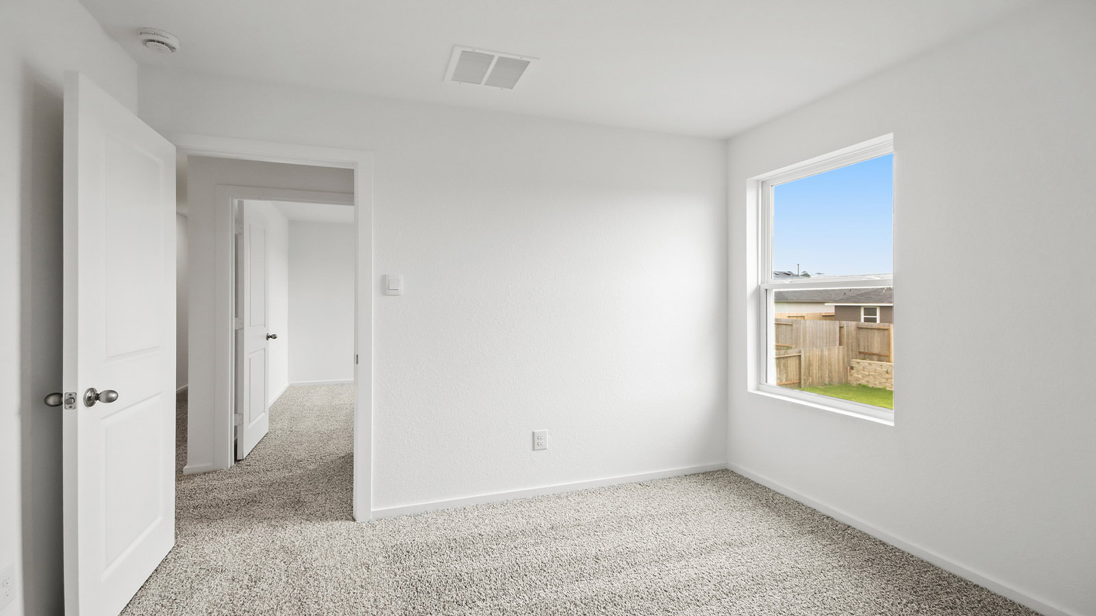 Second level secondary bedroom with carpet flooring and bright window