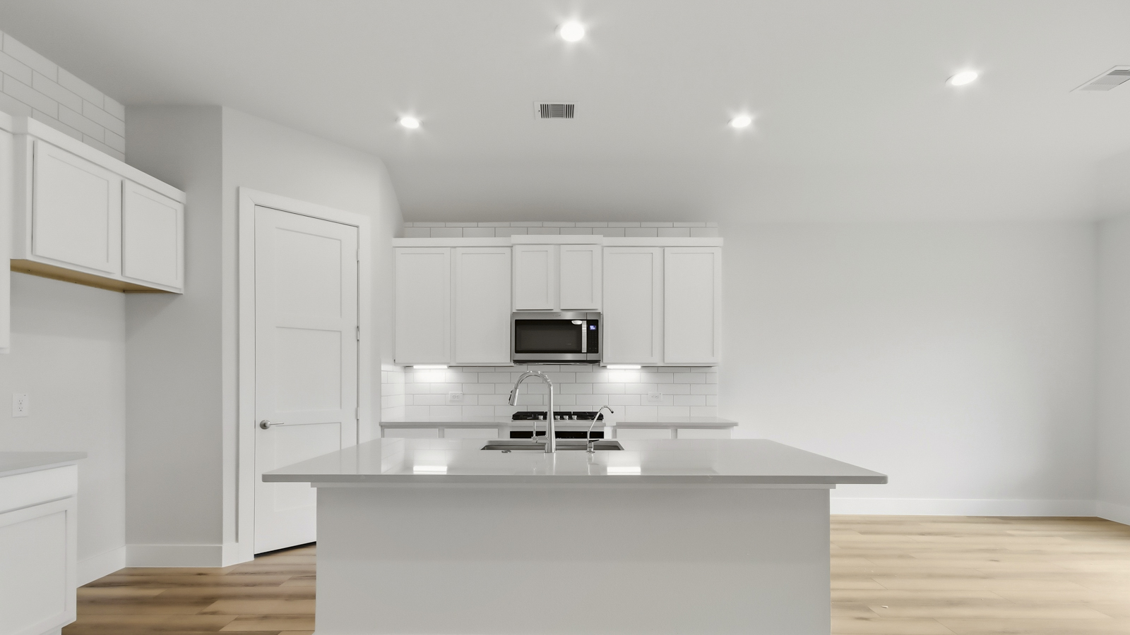 Kitchen with quartz countertops and marden hardware and an island and vinyl floor