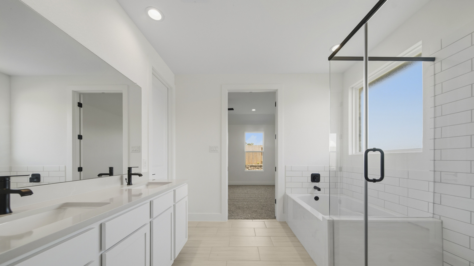 Primary bathroom with soaker tub and tile shower with semi frameless glass in Magnolia TX