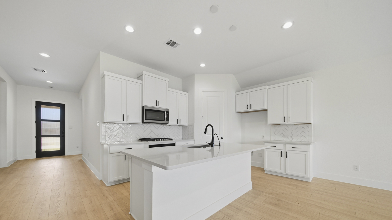 Kitchen with quartz countertops and marden hardware and an island and vinyl floor