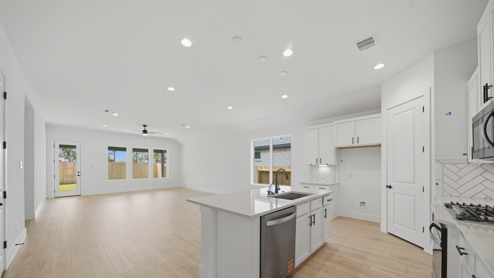 Open concept living, dining, and kitchen area with vinyl flooring and bright windows