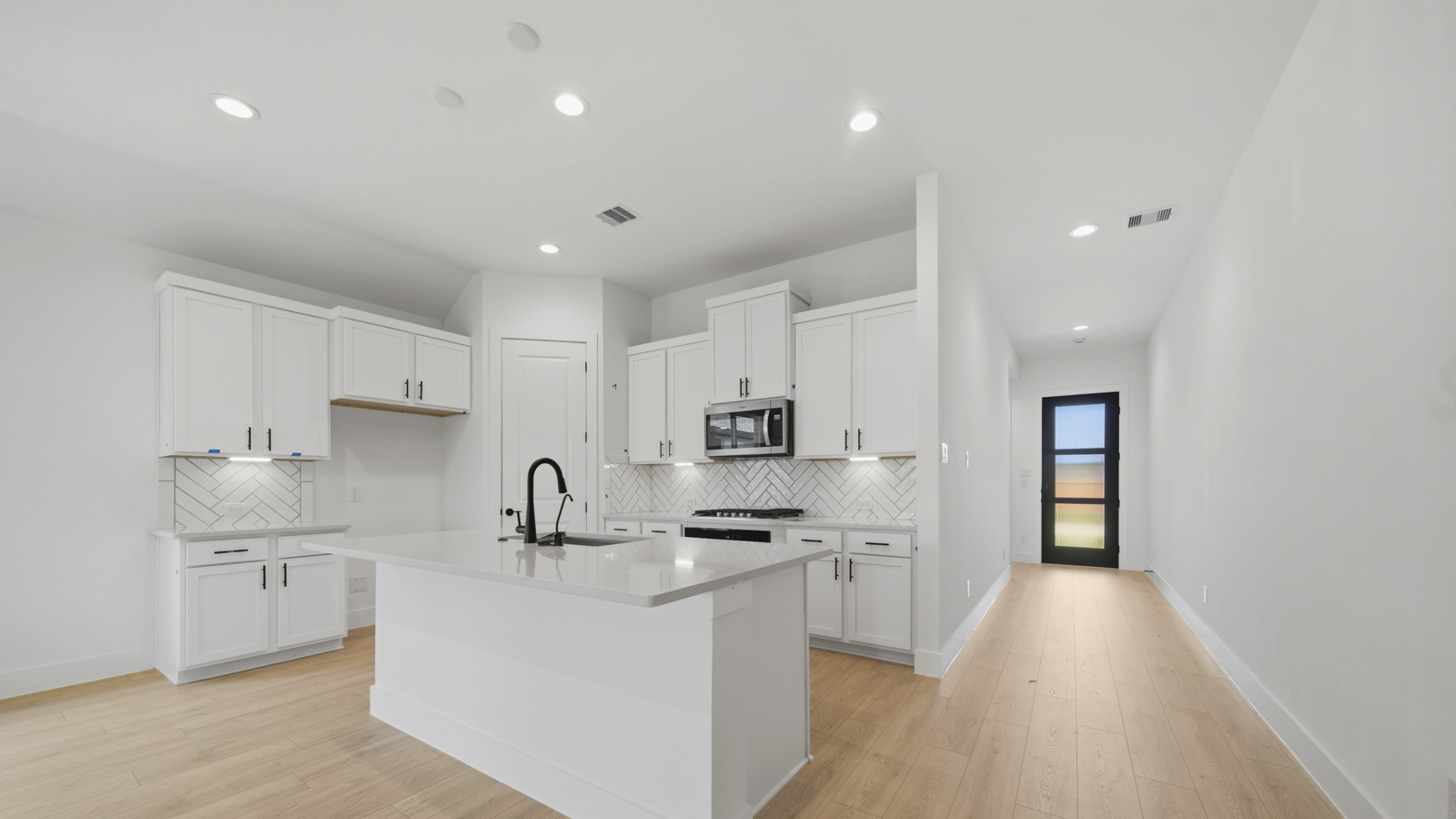 Kitchen with quartz countertops and marden hardware and an island and vinyl floor