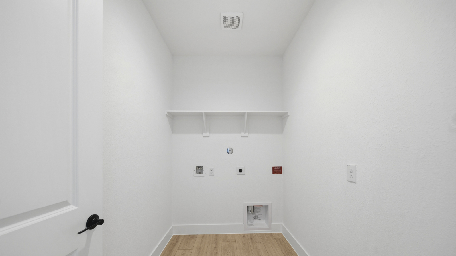 Utility room with storage located off the entry hallway and garage door
