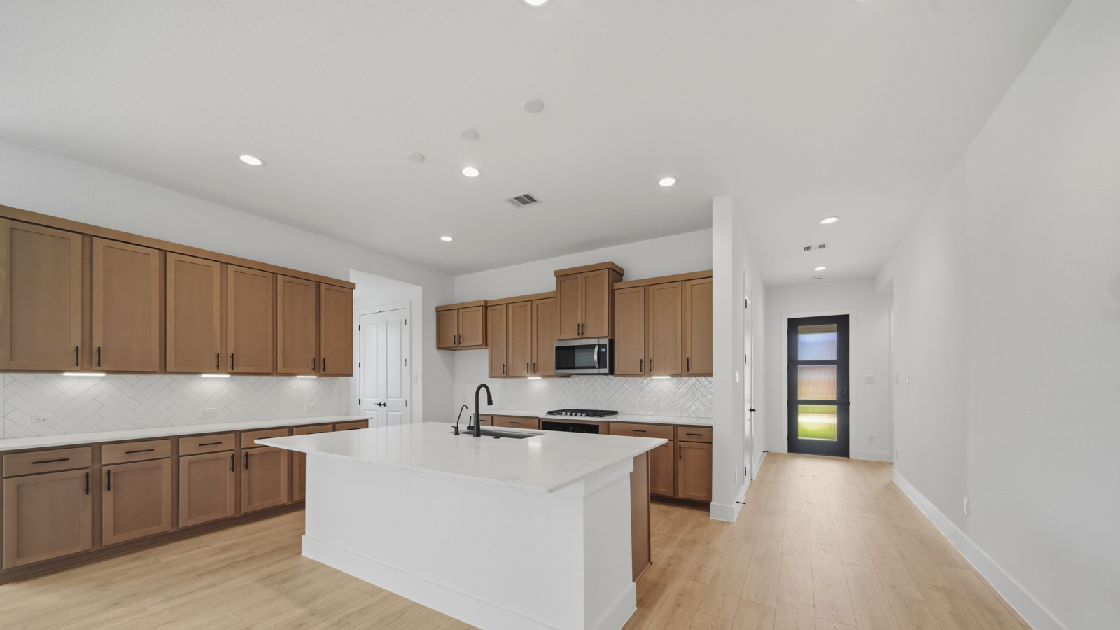 Kitchen with quartz countertops and marden hardware and an island and vinyl floor