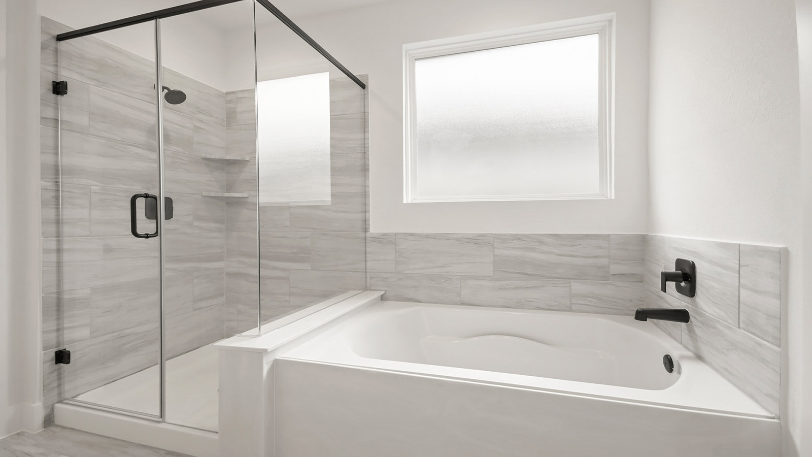 Primary bathroom with soaker tub and tile shower with semi frameless glass in Magnolia TX