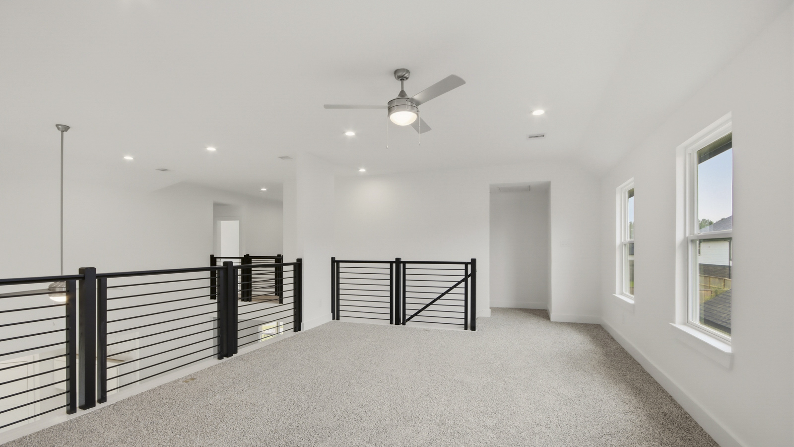 Second story game room with carpet flooring with bright windows in this multi functional space in Conroe TX