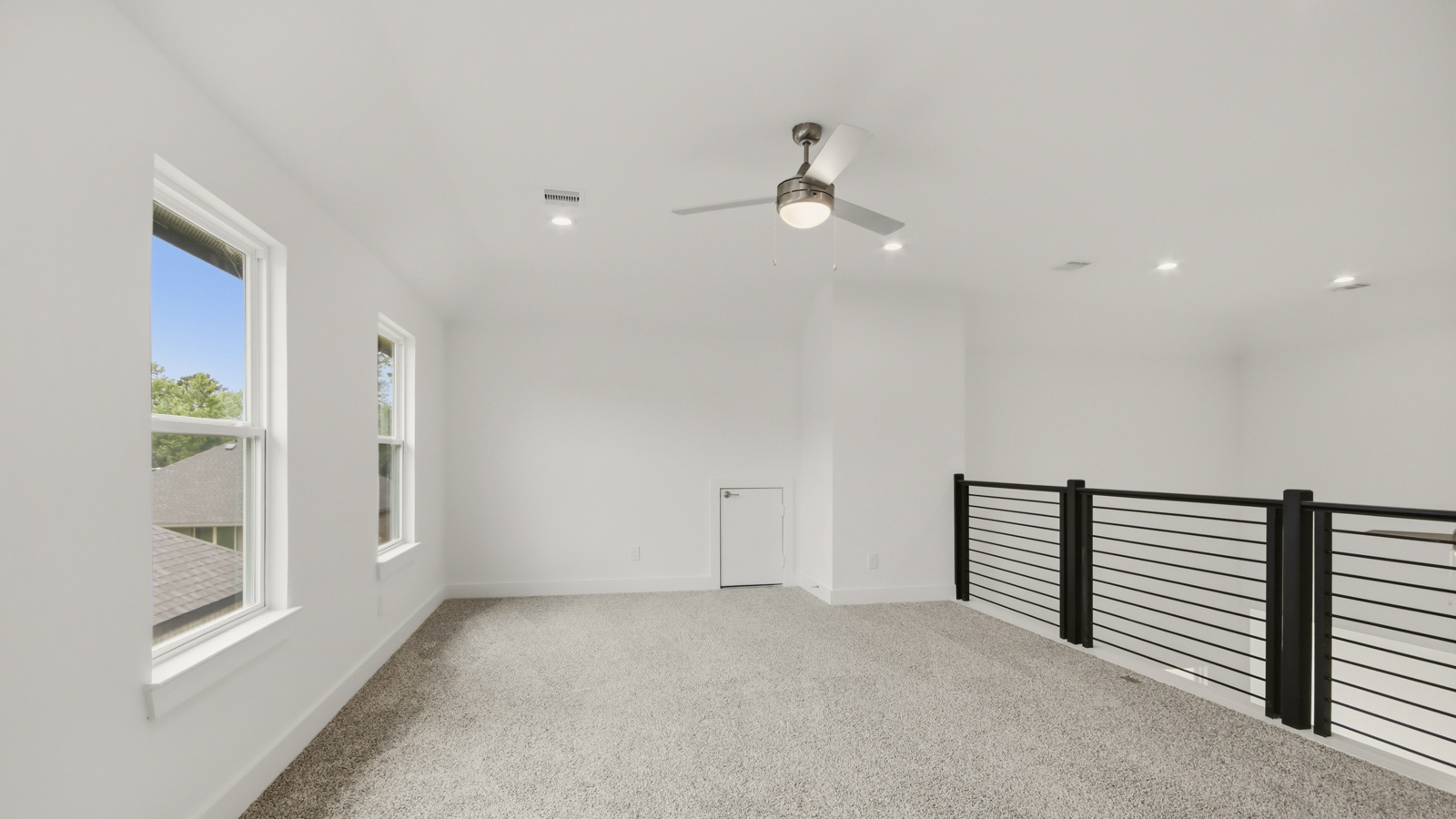 Second story game room with carpet flooring with bright windows in this multi functional space in Conroe TX