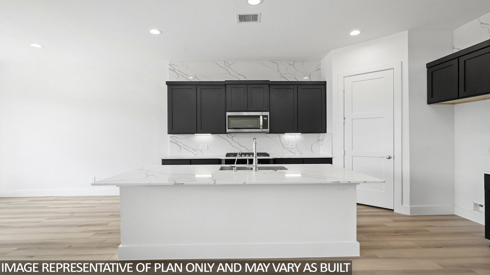 Open kitchen with an island, stainless steel appliances, dark cabinets, white walls, and vinyl wood flooring.