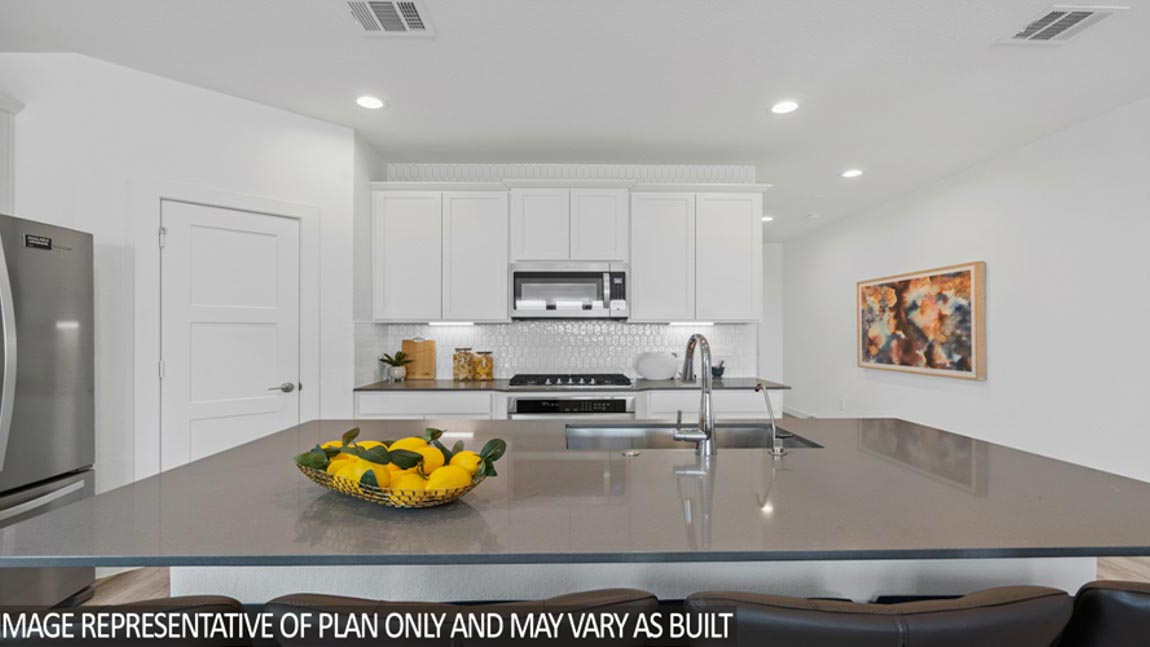 Open kitchen with an island, stainless steel appliances, white cabinets, white walls, and vinyl wood flooring.