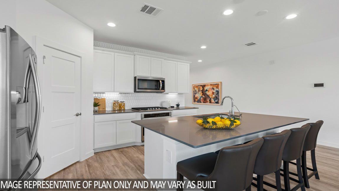 Open kitchen with an island, stainless steel appliances, white cabinets, white walls, and vinyl wood flooring.