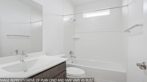 bathroom with bath surround tile, cabinets and upgraded fixtures.