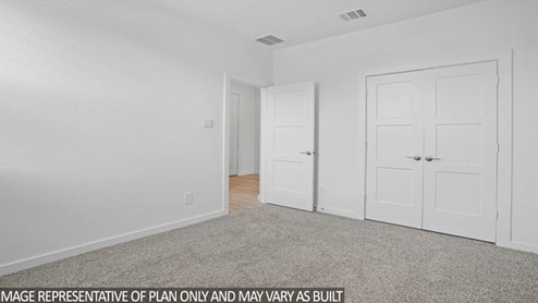 bedroom with carpet and walk in closet with double doors.