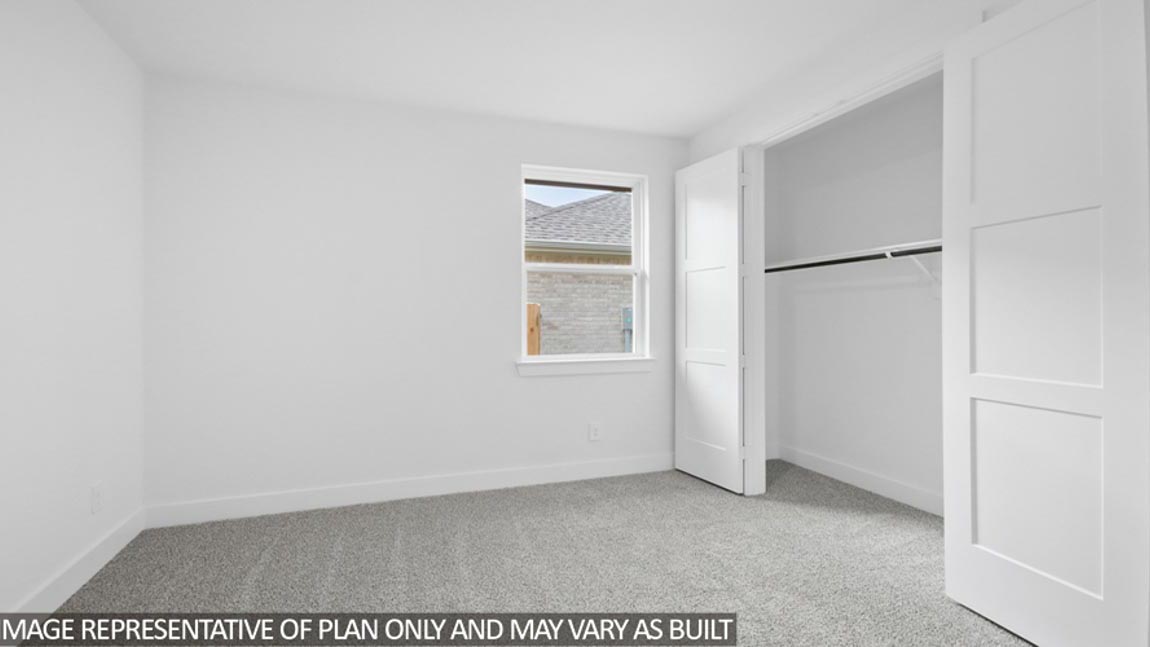 Secondary bedroom with carpet flooring and bright window.