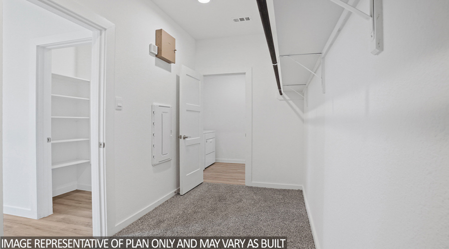 Primary walk-in closet with overhead storage space.