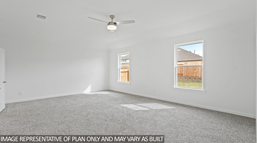 Primary bedroom with carpet flooring and two bright windows.