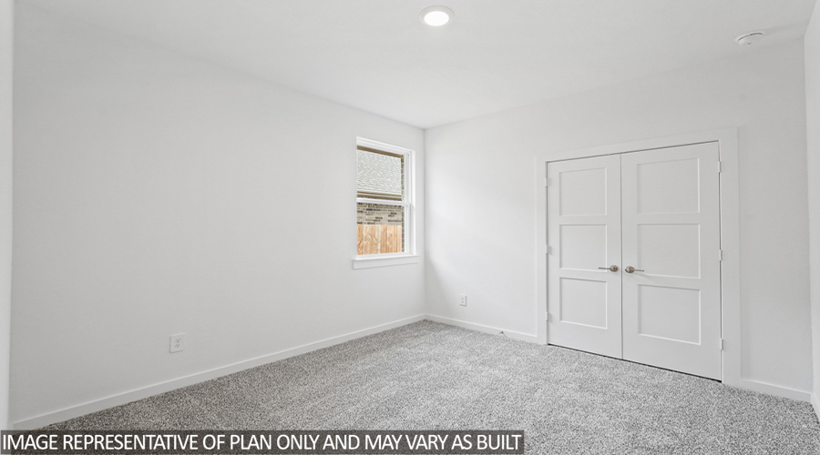 Secondary bedroom with carpet flooring and a two-car garage.